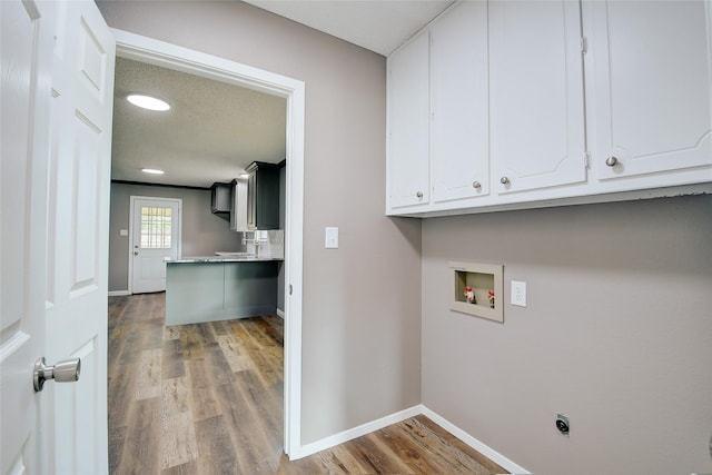 clothes washing area featuring hookup for a washing machine, wood finished floors, baseboards, cabinet space, and electric dryer hookup