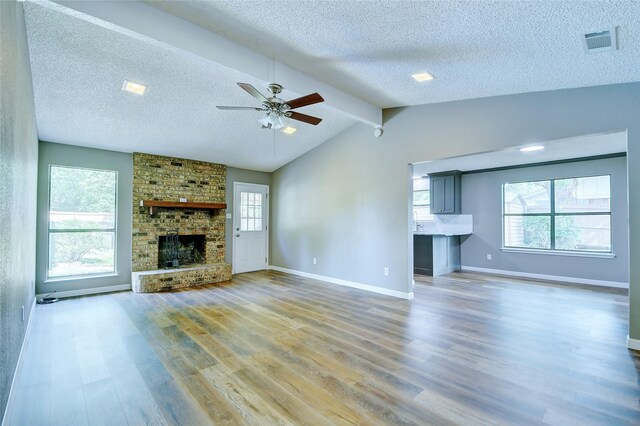 unfurnished living room with light wood-style flooring, a brick fireplace, visible vents, and baseboards