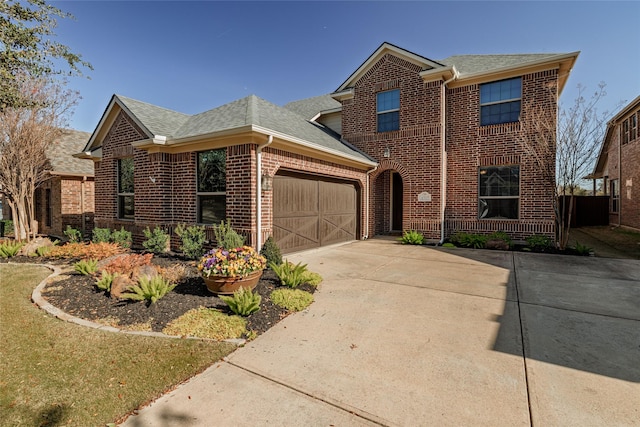 traditional-style house with brick siding, an attached garage, concrete driveway, and roof with shingles