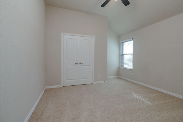 unfurnished bedroom with baseboards, light colored carpet, lofted ceiling, and a ceiling fan