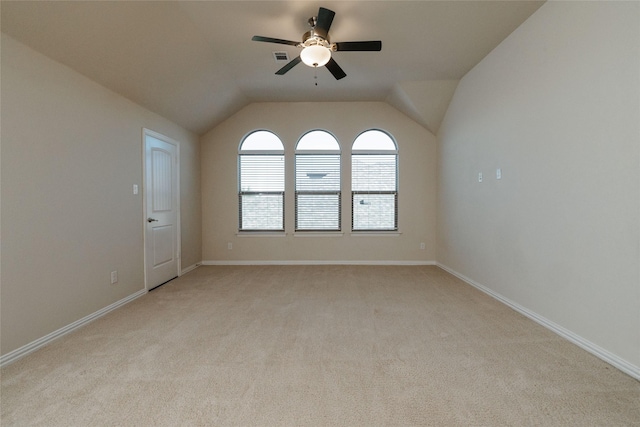 spare room with light colored carpet, baseboards, a ceiling fan, and vaulted ceiling