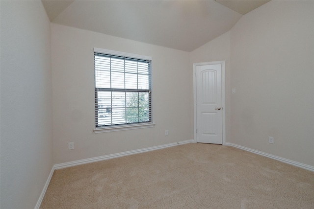 spare room featuring light carpet, baseboards, and vaulted ceiling