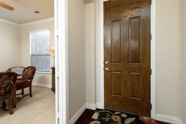 foyer featuring visible vents, baseboards, ornamental molding, a ceiling fan, and dark colored carpet