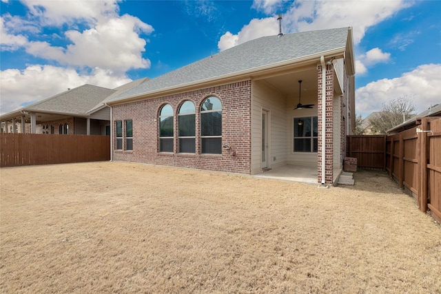 back of property with a ceiling fan, a fenced backyard, a shingled roof, brick siding, and a patio area