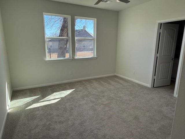 carpeted spare room featuring ceiling fan and baseboards