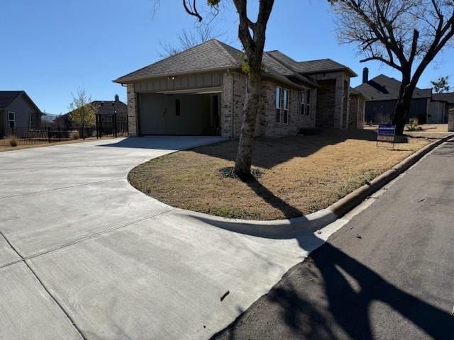 view of side of home featuring a garage, concrete driveway, fence, and stone siding