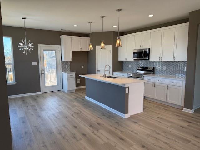 kitchen with appliances with stainless steel finishes, white cabinets, light countertops, and a sink