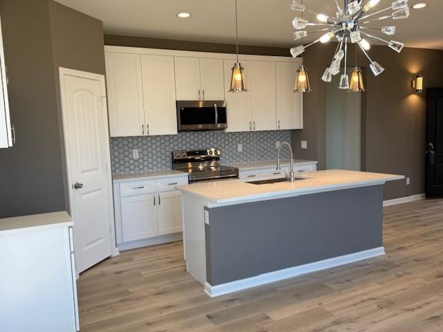 kitchen featuring white cabinetry, stainless steel appliances, a sink, and light countertops