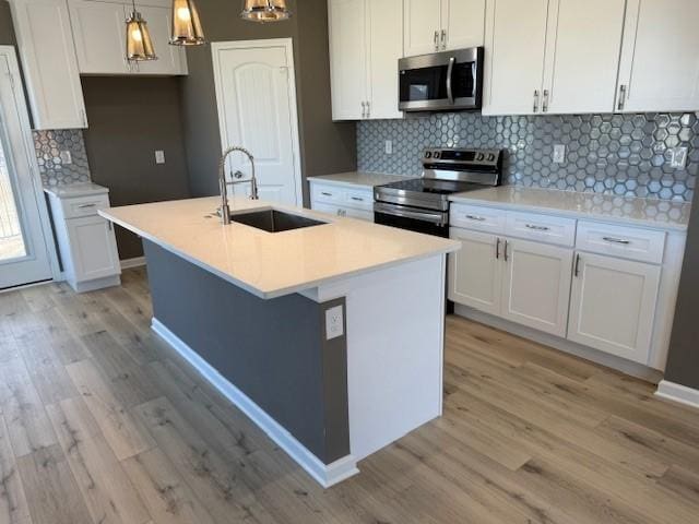 kitchen featuring stainless steel appliances, light wood finished floors, a sink, and white cabinetry