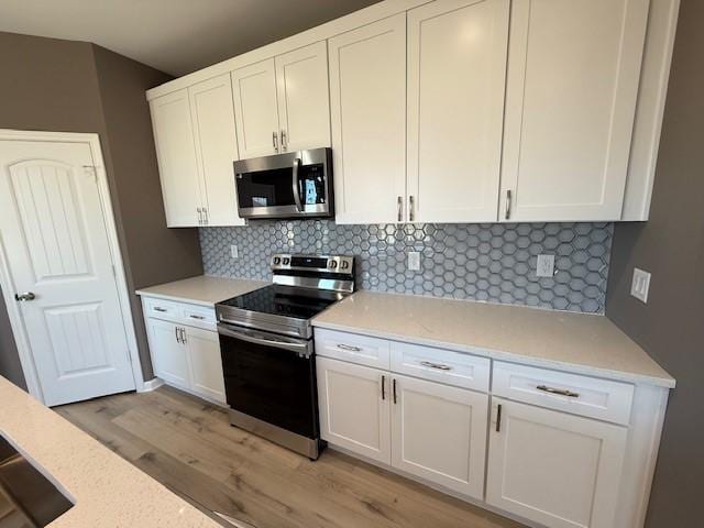 kitchen featuring white cabinetry, appliances with stainless steel finishes, tasteful backsplash, and light wood-style flooring