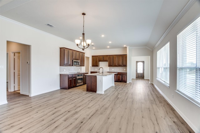 kitchen with visible vents, open floor plan, a kitchen island with sink, stainless steel appliances, and backsplash