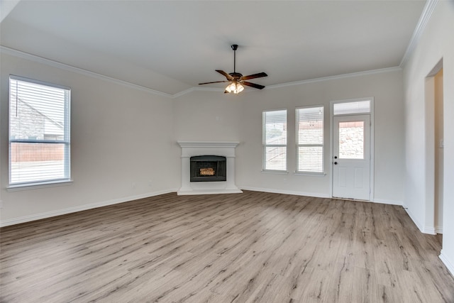 unfurnished living room with baseboards, ornamental molding, a fireplace with raised hearth, and wood finished floors