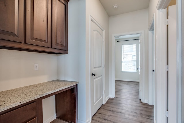 corridor with baseboards and light wood-style floors