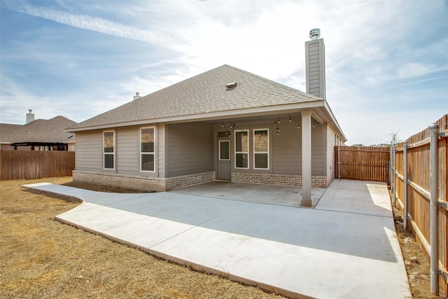 rear view of property with a patio area, a fenced backyard, a chimney, and brick siding