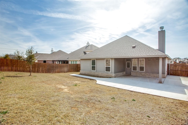 back of house with brick siding, a chimney, a lawn, a patio area, and a fenced backyard