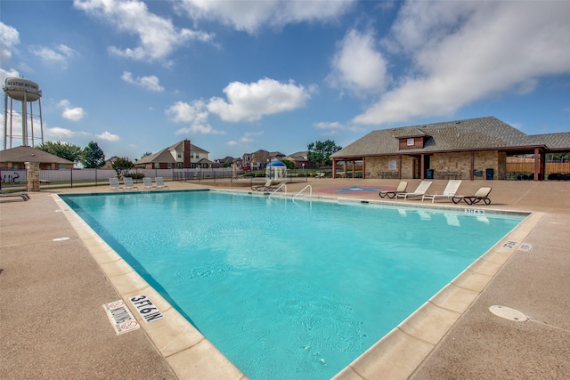 pool with a patio area and fence