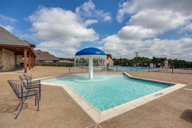 community pool with a patio area and fence