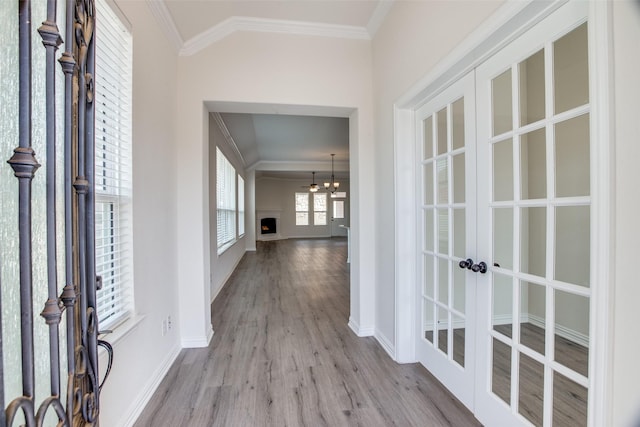 hall with ornamental molding, a chandelier, wood finished floors, and french doors