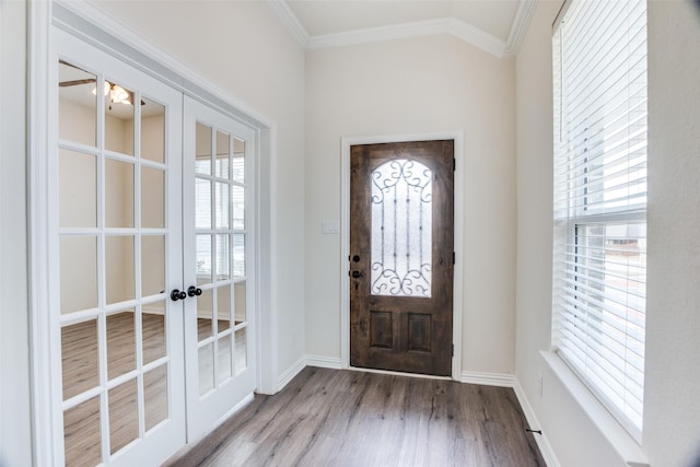 foyer with french doors, crown molding, lofted ceiling, wood finished floors, and baseboards