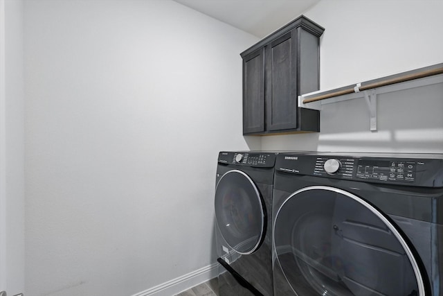 laundry room featuring cabinet space, baseboards, washer and clothes dryer, and wood finished floors