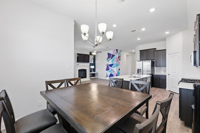 dining room featuring a glass covered fireplace, visible vents, recessed lighting, and ceiling fan with notable chandelier