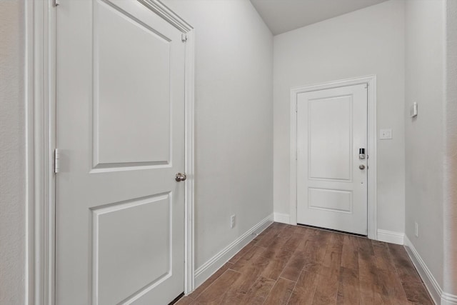 doorway with dark wood finished floors and baseboards