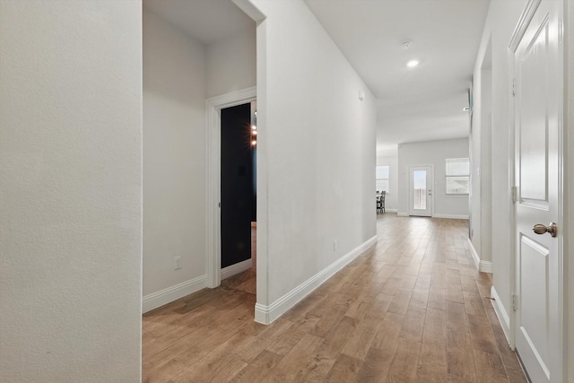 corridor with light wood-style flooring and baseboards