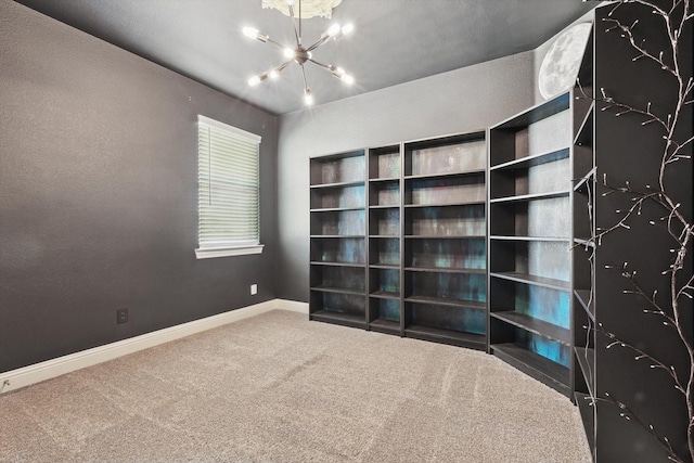 unfurnished room with a notable chandelier, baseboards, and carpet flooring