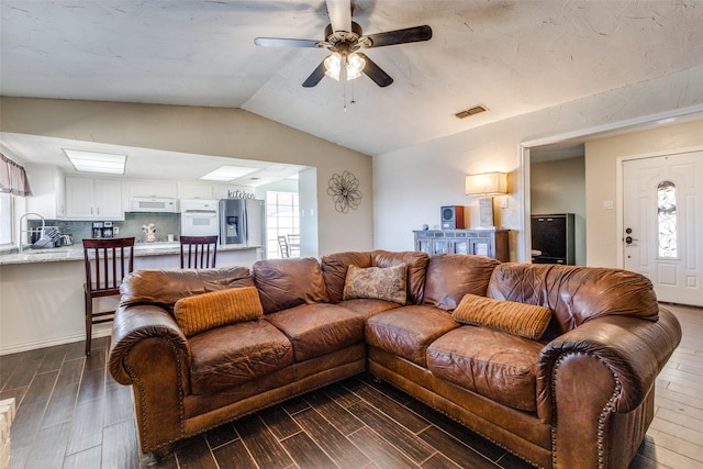 living area featuring lofted ceiling, visible vents, wood finish floors, and a wealth of natural light