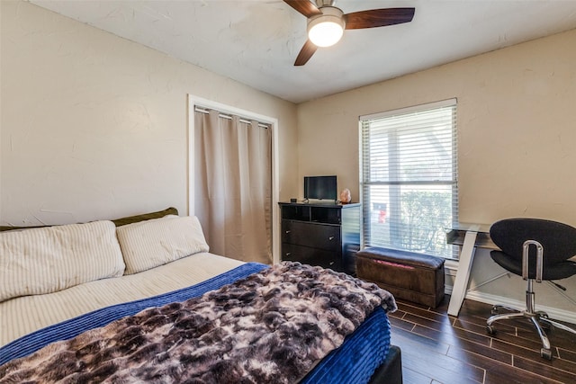 bedroom featuring dark wood-type flooring, a textured wall, baseboards, and a ceiling fan