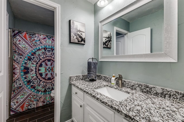 bathroom featuring toilet, curtained shower, wood finished floors, and vanity