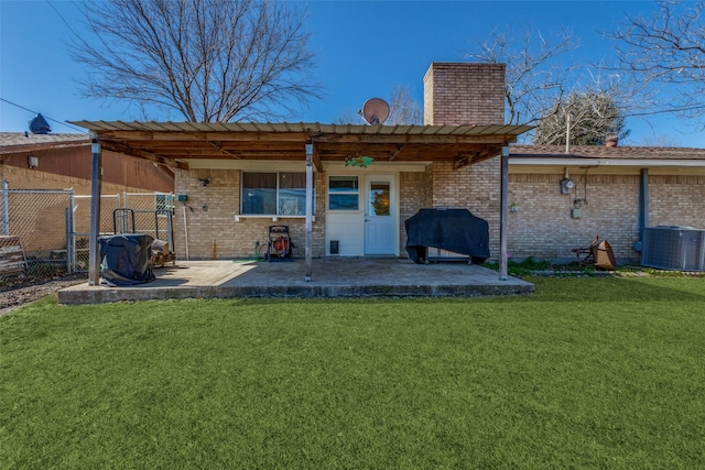 back of property featuring brick siding, fence, a lawn, and a patio