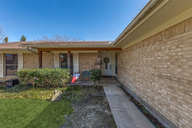 entrance to property with a porch and brick siding