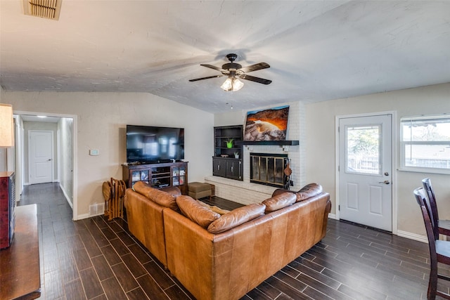 living area with lofted ceiling, wood tiled floor, a fireplace, and visible vents