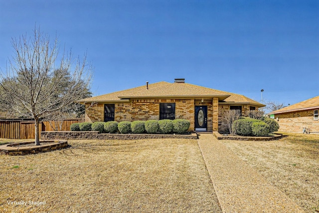 view of front of property featuring roof with shingles, fence, and brick siding