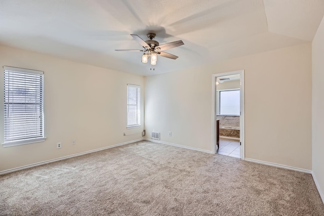 carpeted empty room featuring baseboards, plenty of natural light, visible vents, and a ceiling fan