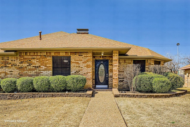 view of front facade with roof with shingles and brick siding