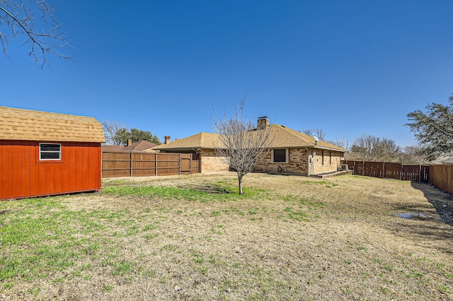 view of yard featuring an outbuilding, a storage unit, and a fenced backyard