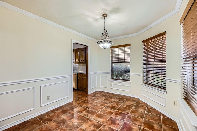 unfurnished dining area with ornamental molding, a wainscoted wall, a decorative wall, and dark tile patterned floors