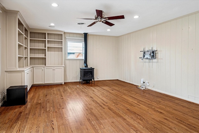 unfurnished living room with hardwood / wood-style floors, a ceiling fan, visible vents, a wood stove, and recessed lighting