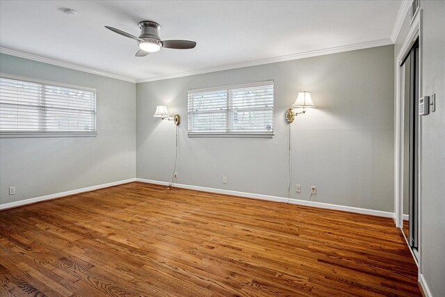 spare room featuring baseboards, a ceiling fan, wood finished floors, and crown molding