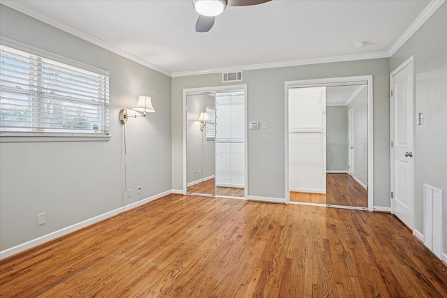 unfurnished bedroom featuring crown molding, wood finished floors, and visible vents