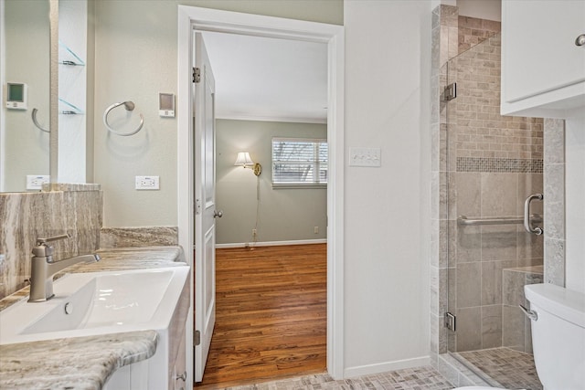 full bath featuring a shower stall, crown molding, wood finished floors, and baseboards