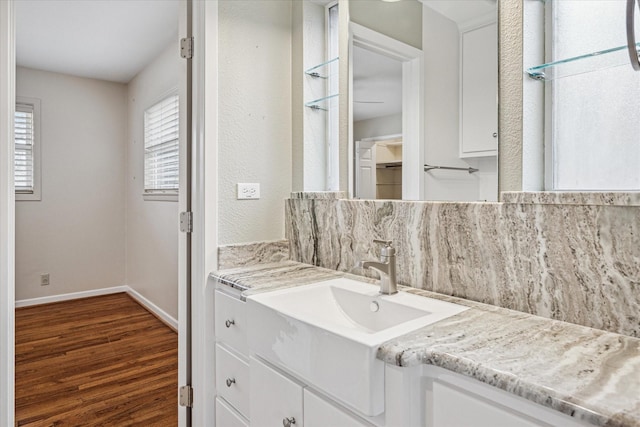 bathroom with decorative backsplash, vanity, wood finished floors, and baseboards