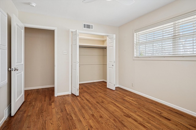 unfurnished bedroom featuring visible vents, baseboards, a closet, and wood finished floors