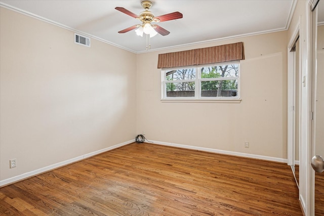 unfurnished bedroom featuring visible vents, crown molding, ceiling fan, baseboards, and wood finished floors