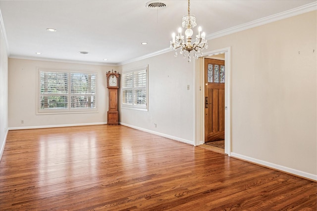 spare room featuring visible vents, baseboards, wood finished floors, and crown molding