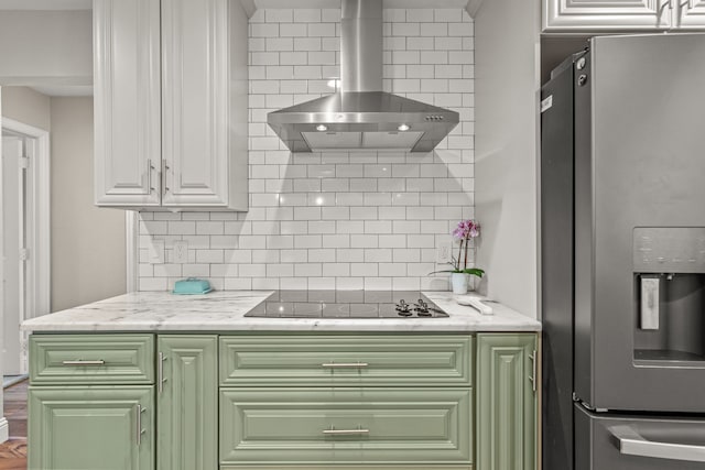 kitchen featuring black electric cooktop, decorative backsplash, wall chimney exhaust hood, and stainless steel refrigerator with ice dispenser