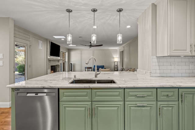 kitchen featuring stainless steel dishwasher, a decorative wall, open floor plan, and a sink