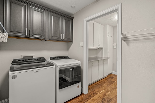 washroom with washer and dryer, cabinet space, light wood finished floors, and a textured ceiling